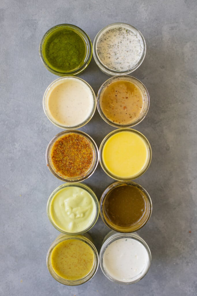 A row of healthy salad dressings in small mason jars
