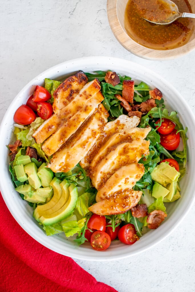 A close up of honey mustard dressing drizzled on a salad