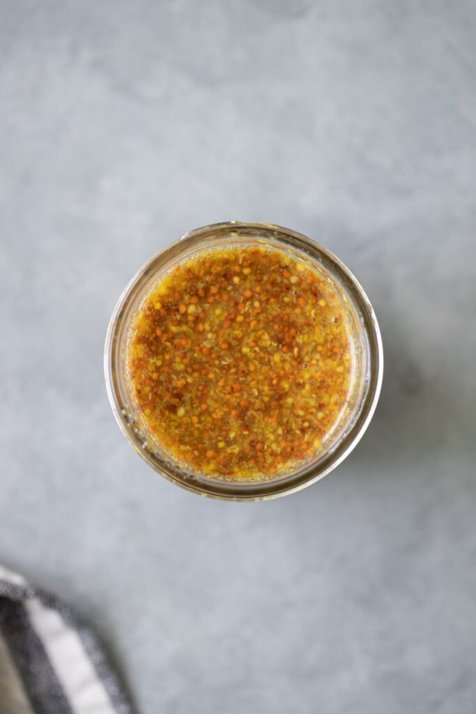 A close up of the best honey mustard dressing in a glass mason jar
