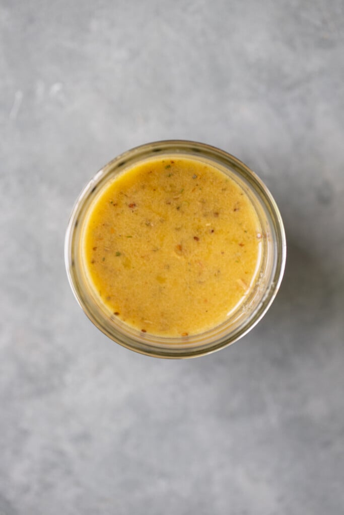 A close up of homemade italian dressing in a glass jar