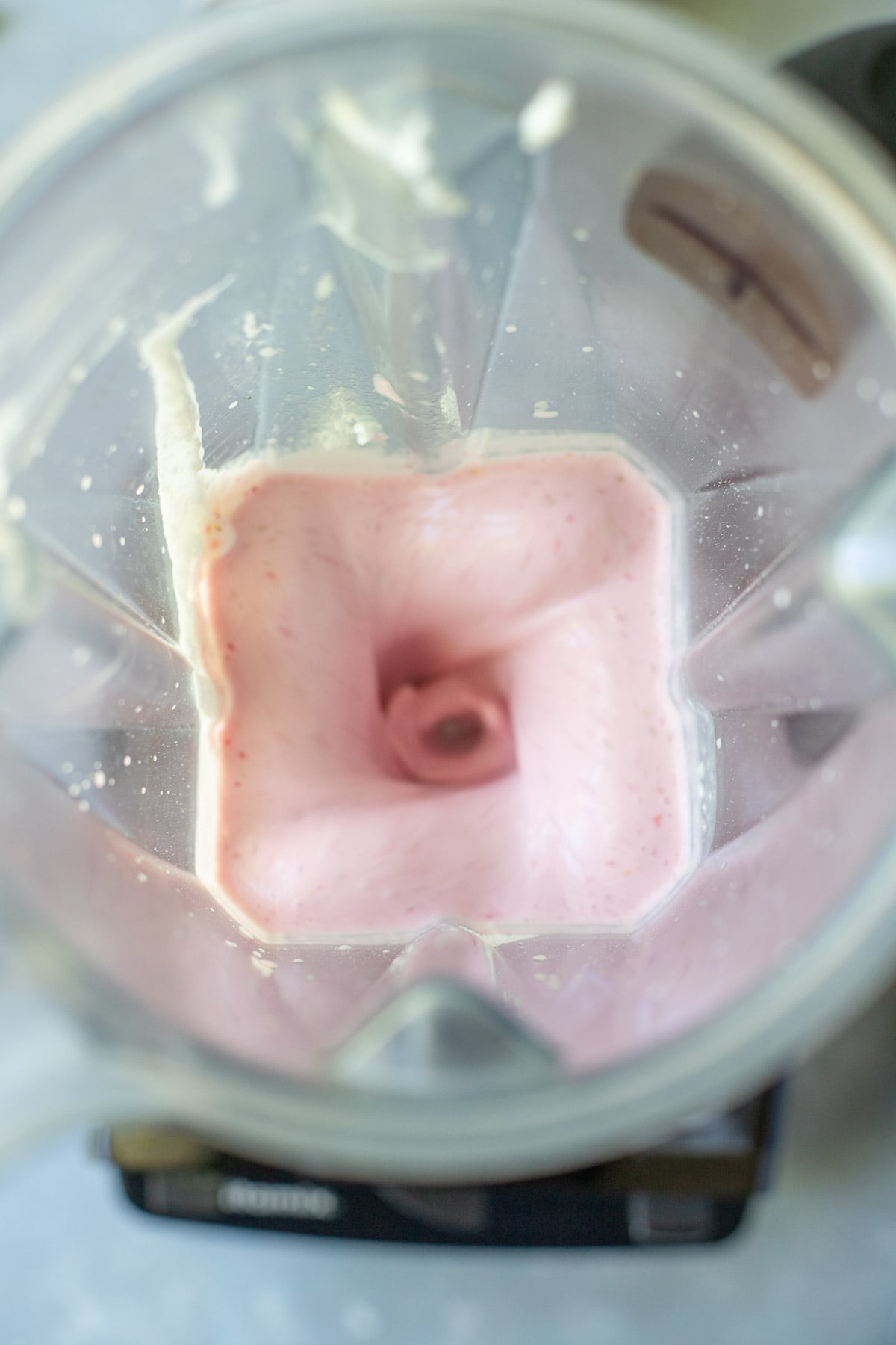 An overhead shot of strawberry smoothie in a blender while blending