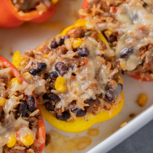 Taco stuffed peppers in a white baking dish on a grey background