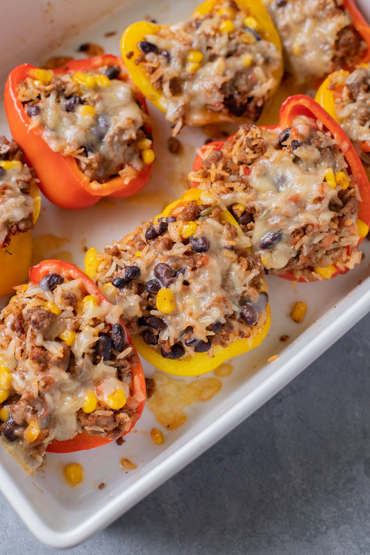 taco stuffed peppers with melty cheese in a white baking dish