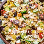 A large wooden bowl of greek chicken pasta salad