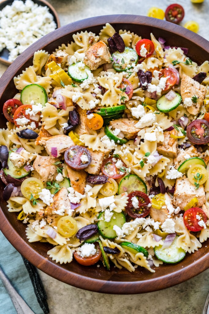 A large wooden bowl of greek chicken pasta salad