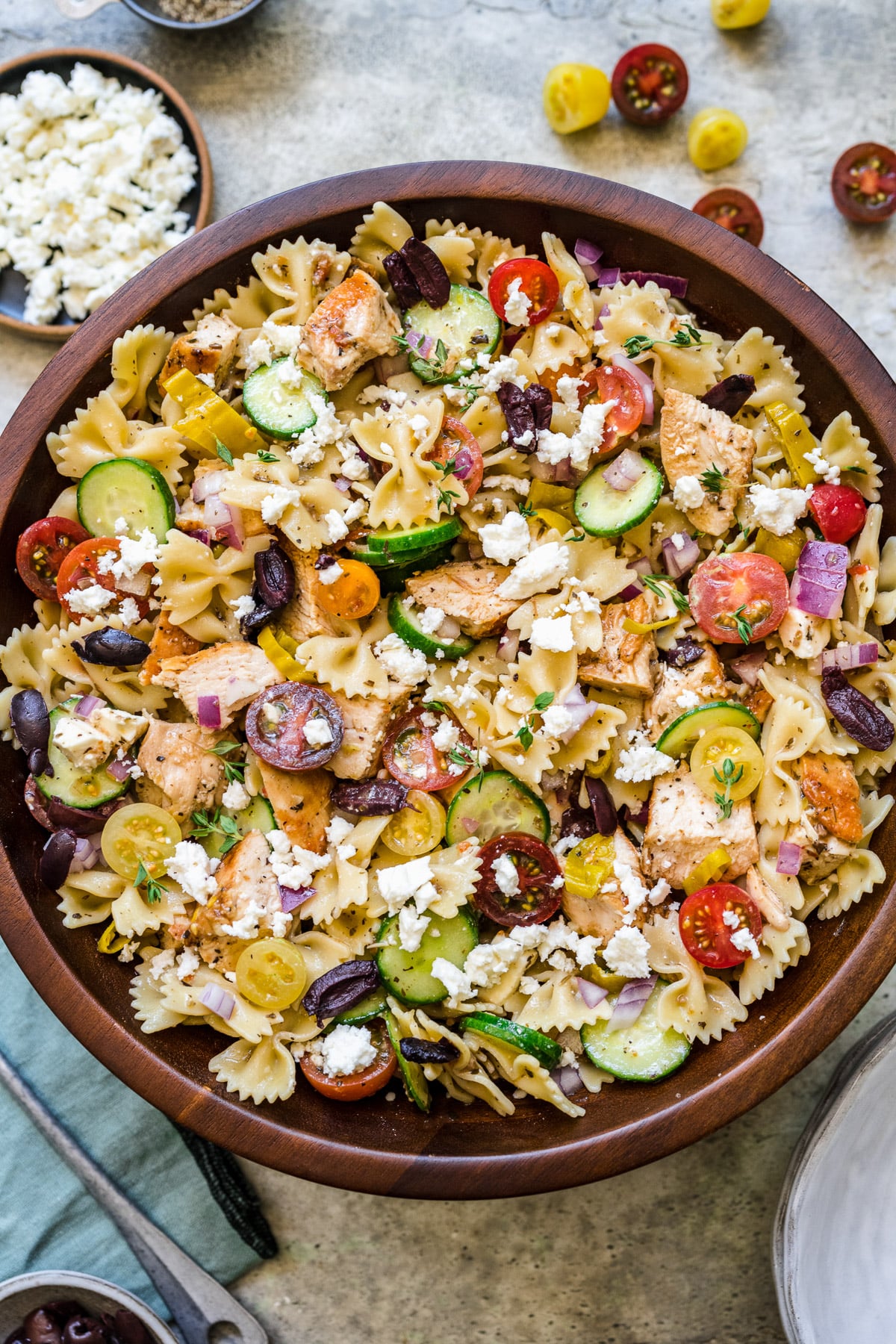 A large wooden bowl of greek chicken pasta salad