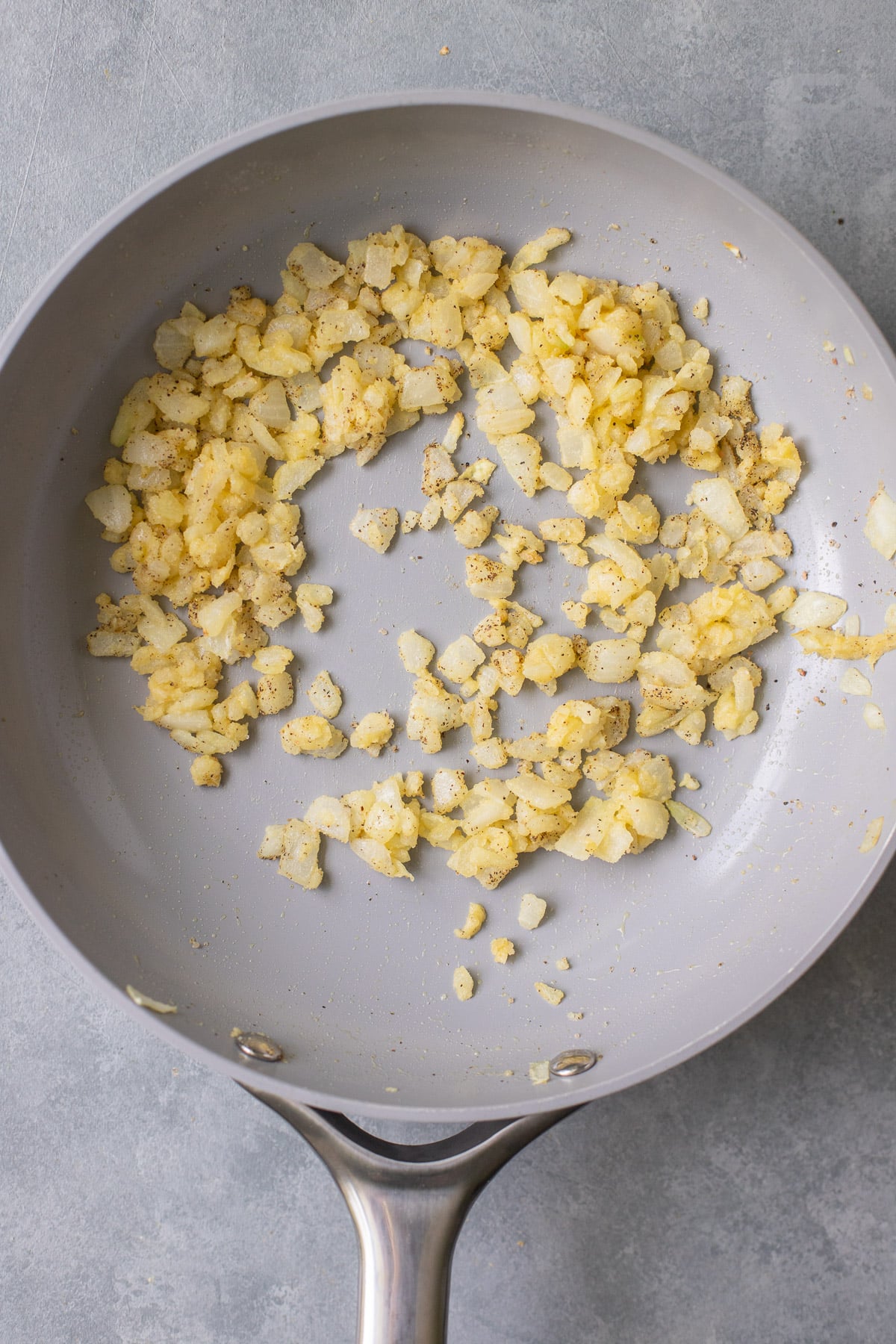 Onions, garlic and flour in a grey pan sauteing for healthy alfredo sauce