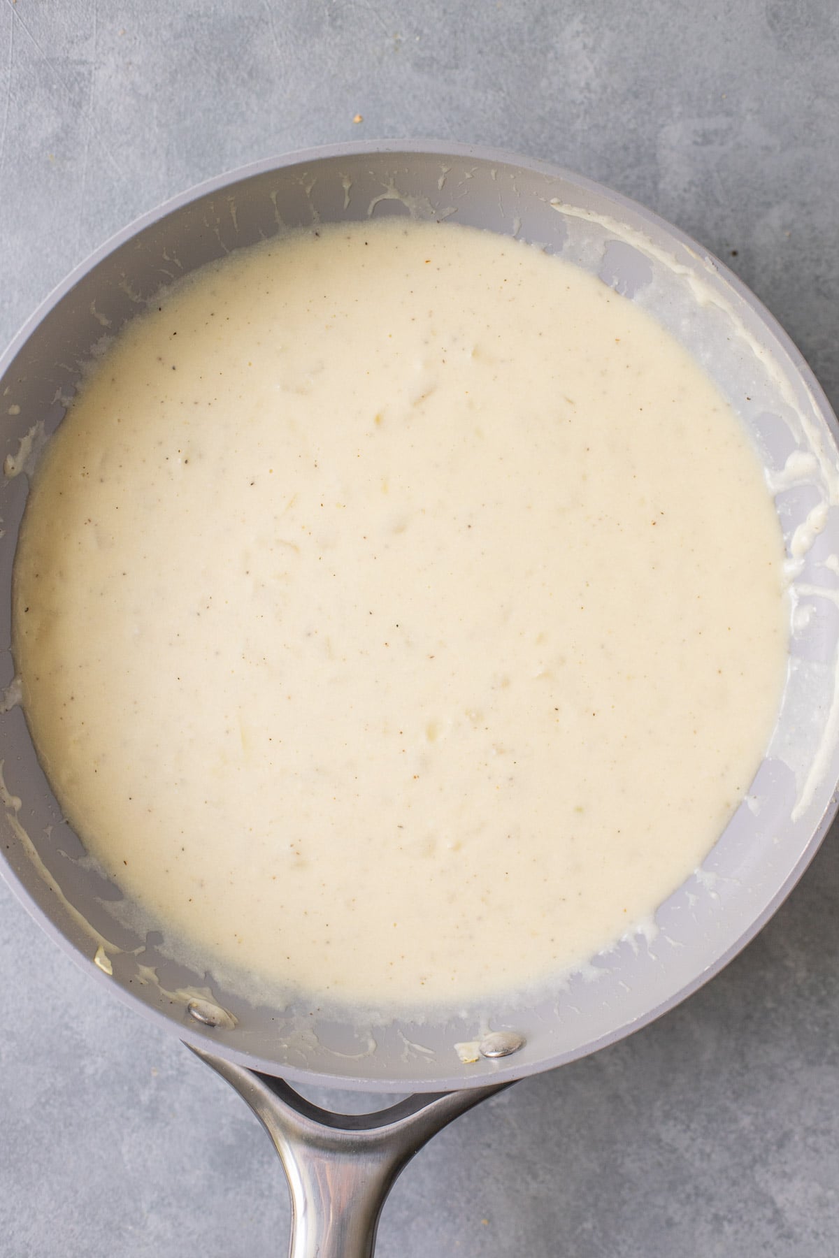 healthy alfredo sauce in a grey pan on a grey background