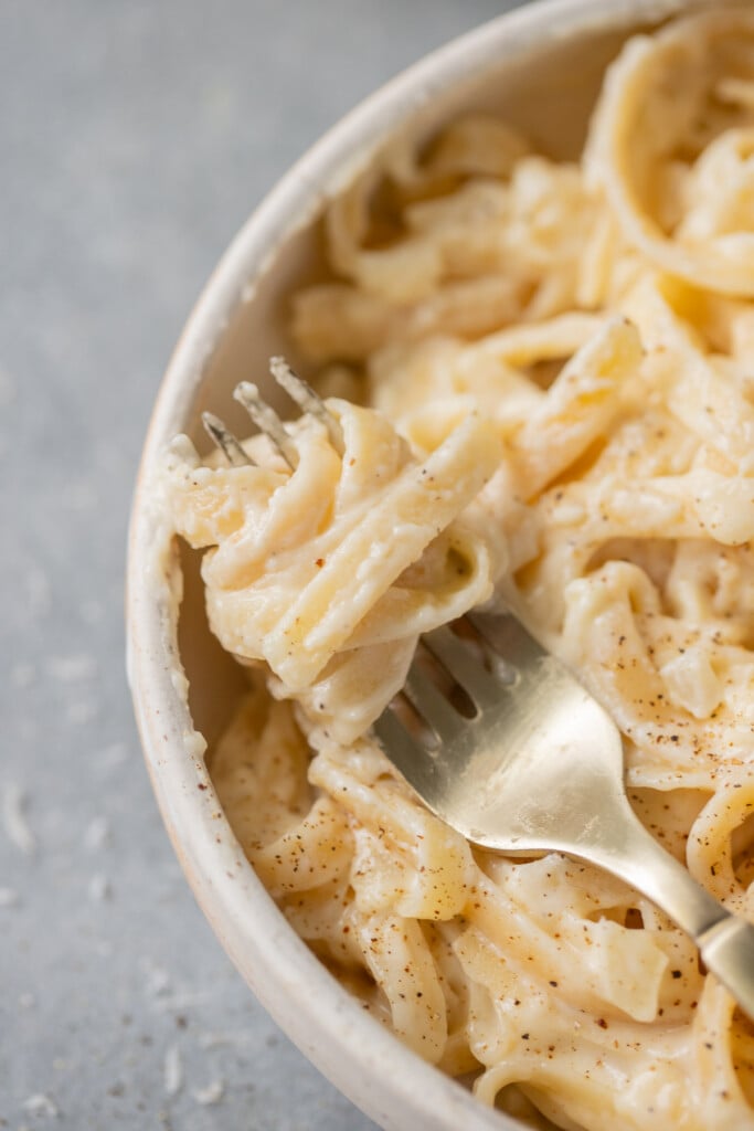 a fork taking a bite out of homemade alfredo sauce healthy