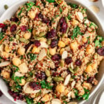 An overhead shot of a bowl of kale quinoa salad on a grey background