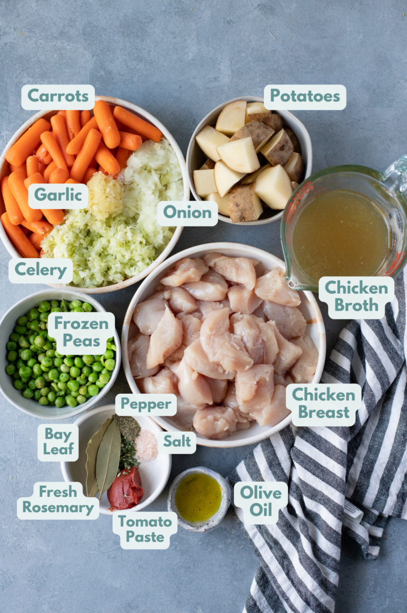 Chicken Stew Instant Pot Ingredients in white bowls on a grey background: boneless skinless chicken breasts, onion, garlic, baby carrots, celery, russet potatoes, frozen peas, tomato paste, olive oil, chicken broth, bay leaf, fresh rosemary, salt & pepper