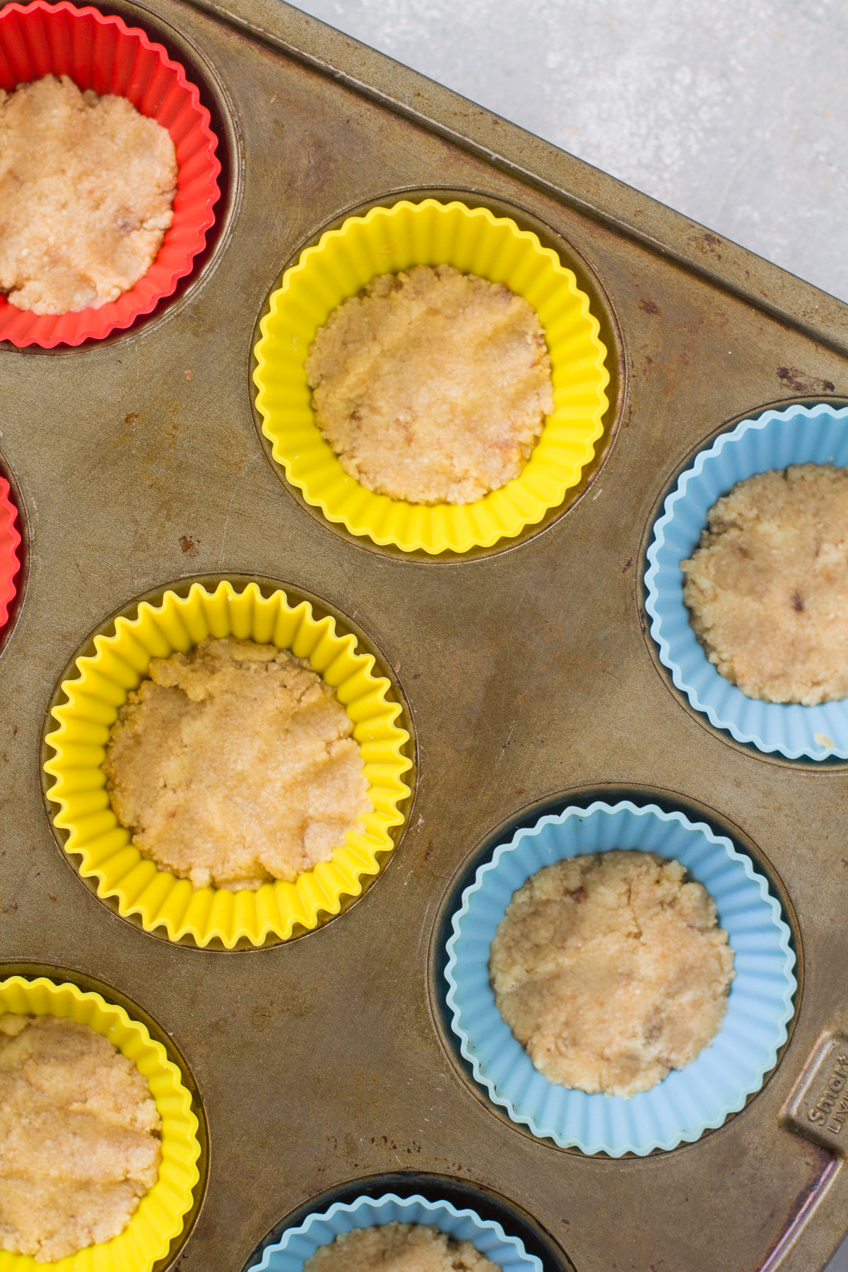 Crust for healthy lime cheesecakes being baked in silicone muffin liners
