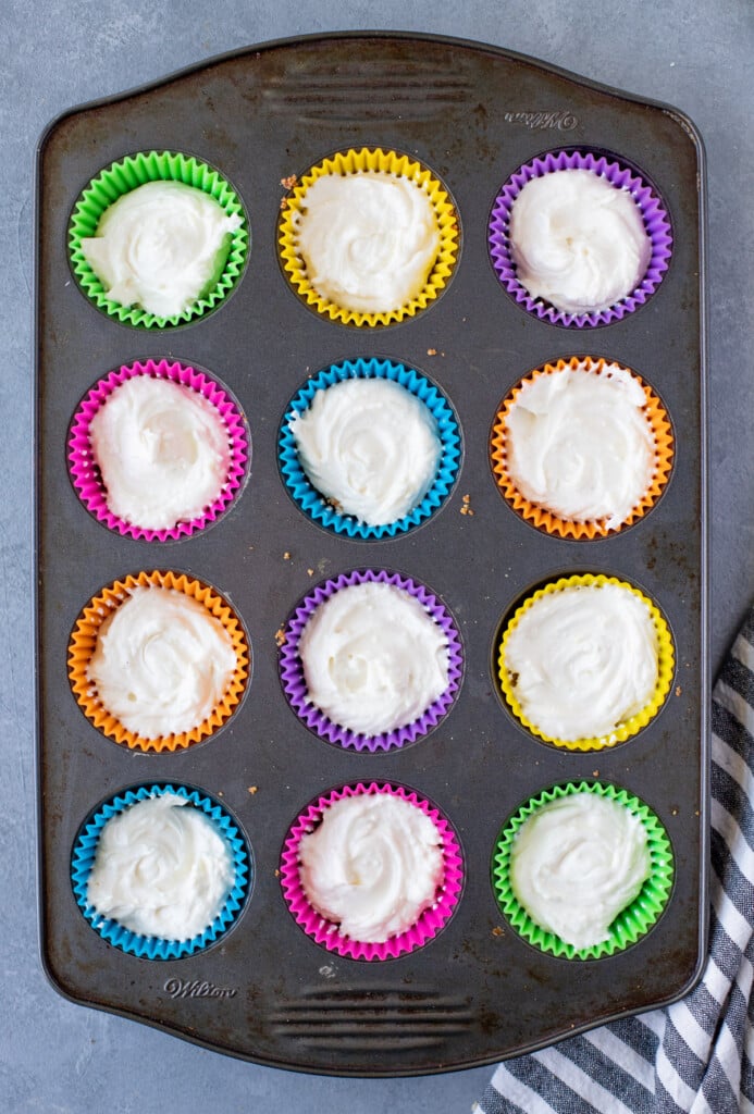 Mini lime cheesecakes in a muffin tin chilling in the refrigerator.
