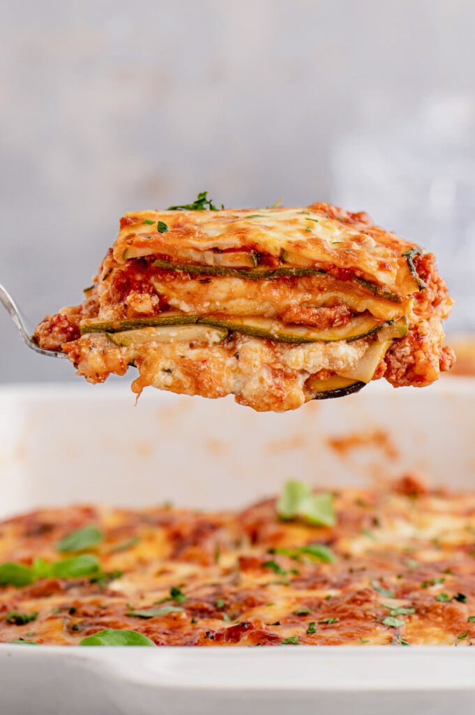 A piece of zucchini lasagna being lifted out of a casserole dish