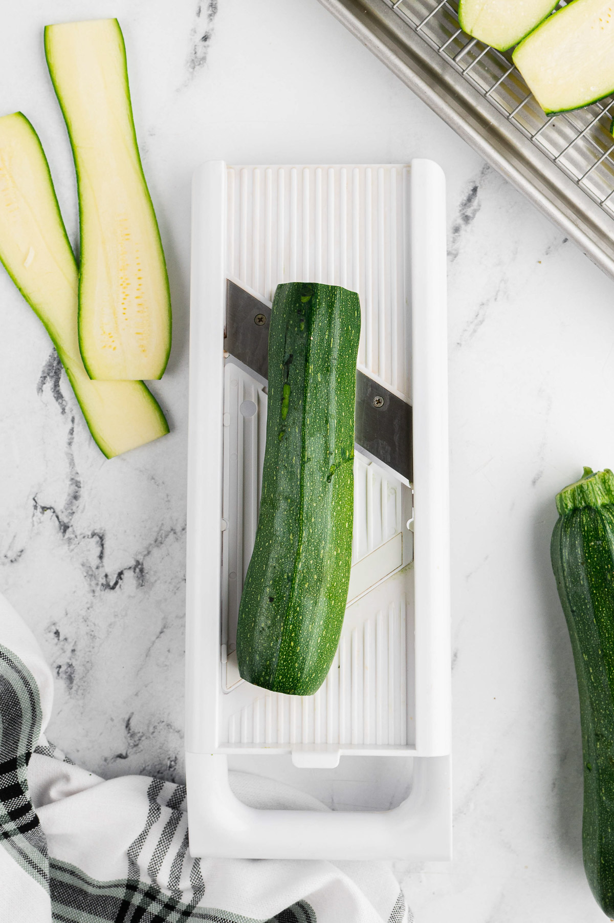 Zucchini on a mandolin slicer to slice for zucchini lasagna