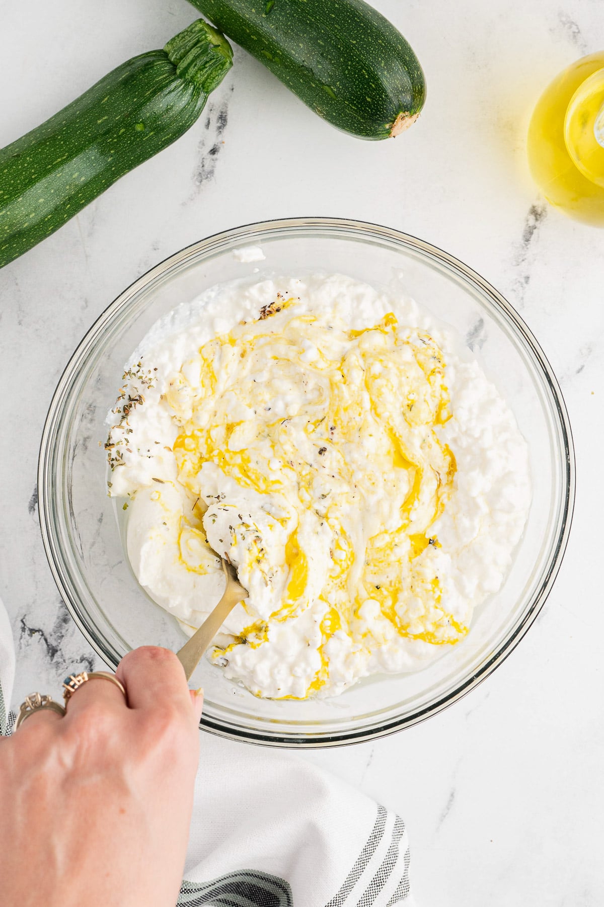 ingredients for ricotta mixture for zucchini lasagna being mixed in a clear bowl