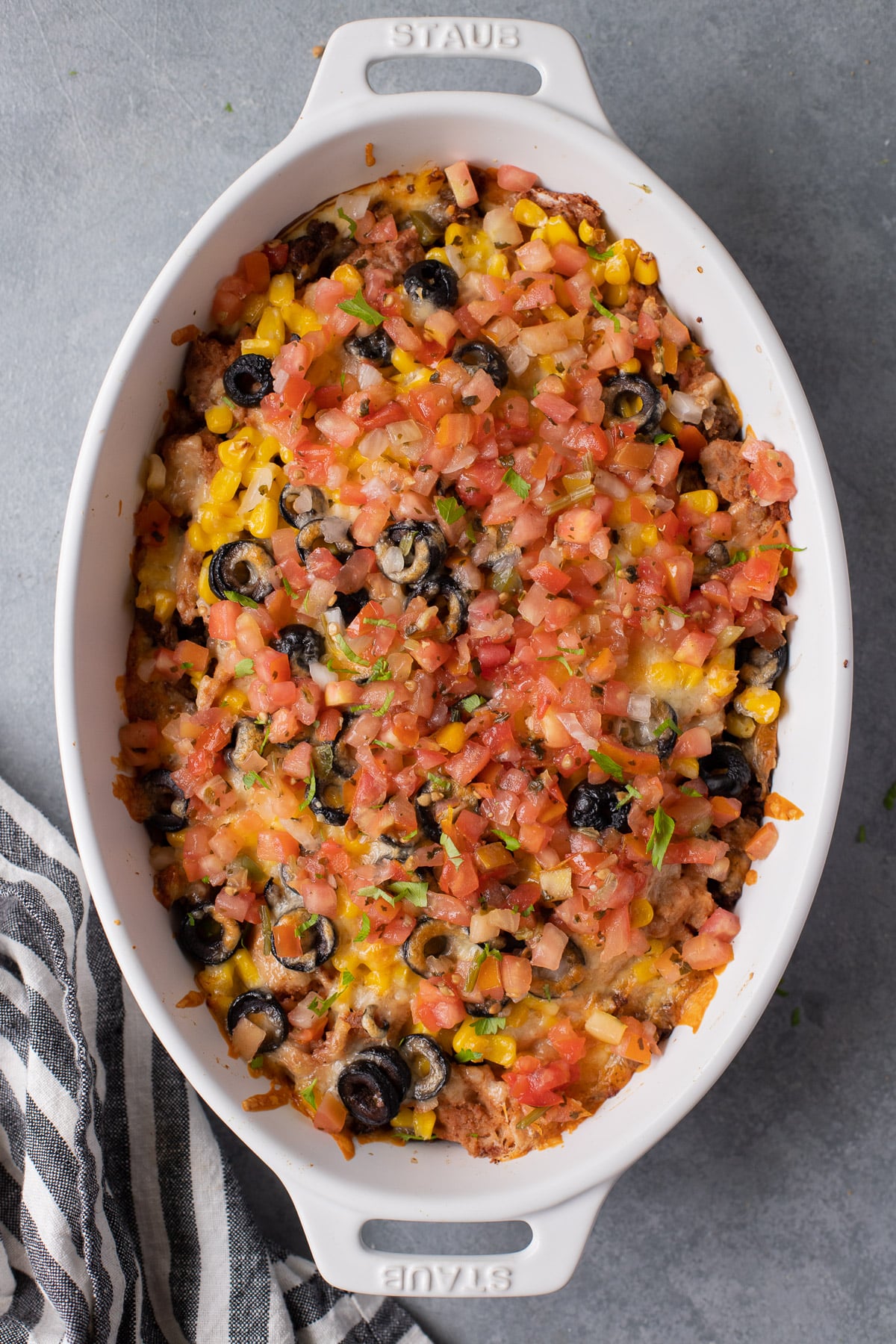 Fully assembled baked seven layer dip in a white baking dish on a grey background
