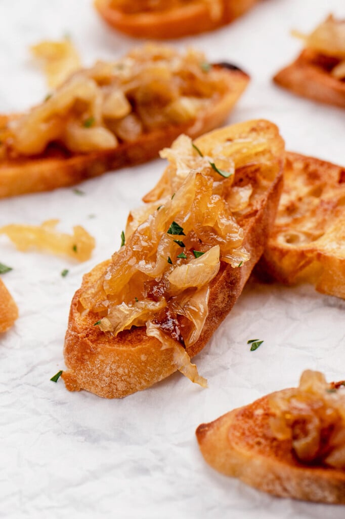Caramelized onions on a toasted baguette with more baguettes in the background