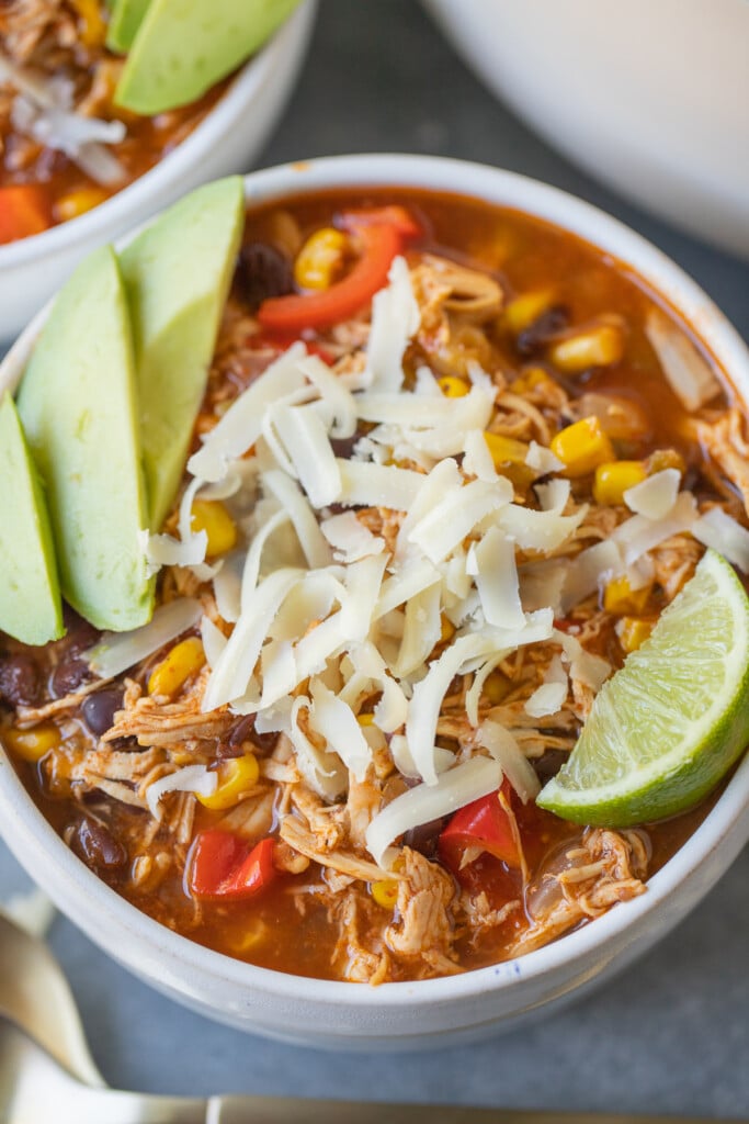 a clouse up of chicken enchilada soup in a white bowl