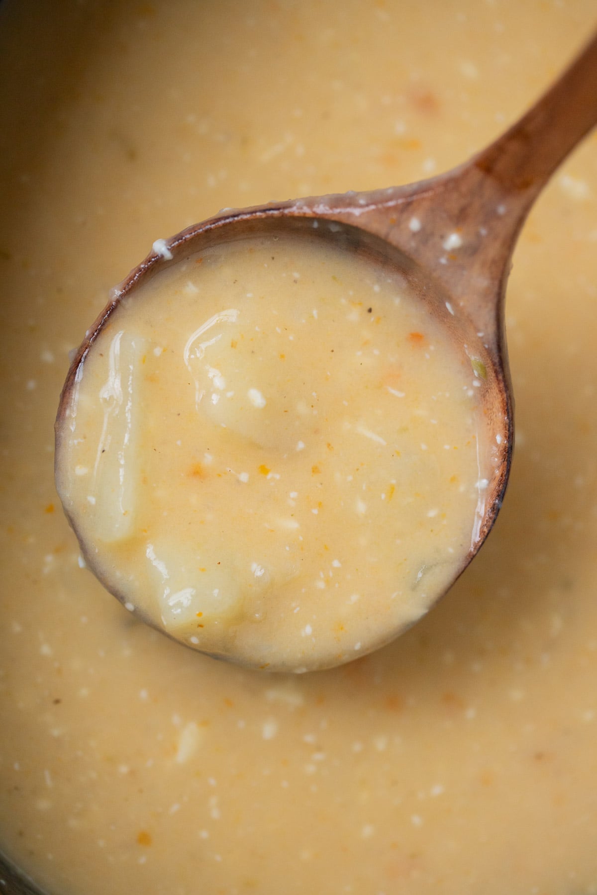 A crock pot of slow cooker potato soup with a ladle taking a scoop out of it