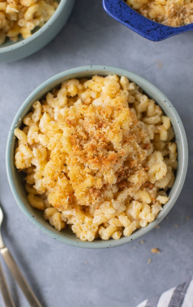 An overhead shot of a blue bowl of healthy mac and cheese on a grey background