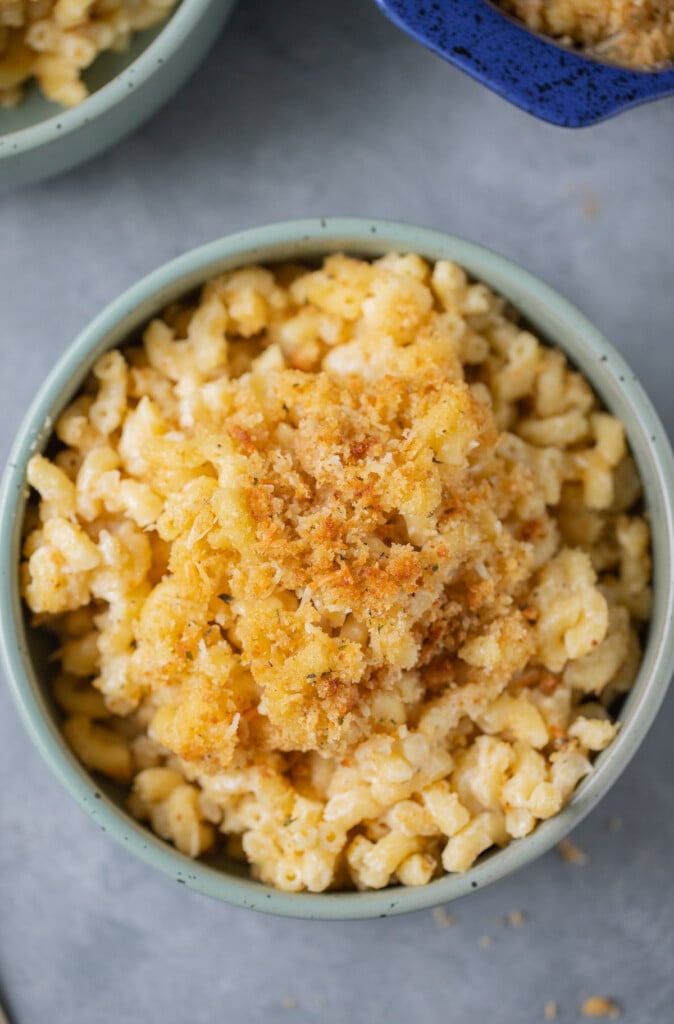 A close shot of a blue bowl of healthy mac and cheese on a grey background