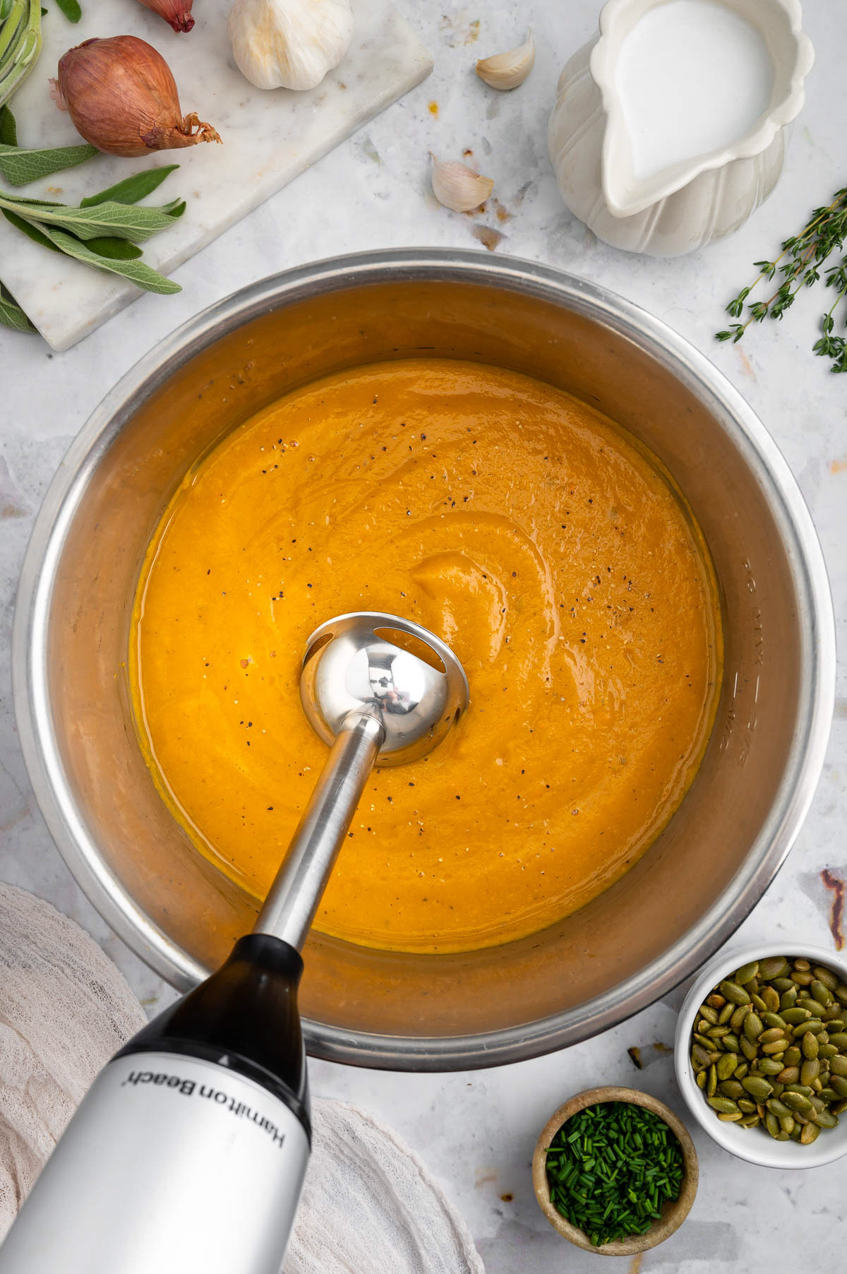Instant pot butternut squash in a pressure cooker being blended with an immersion blender