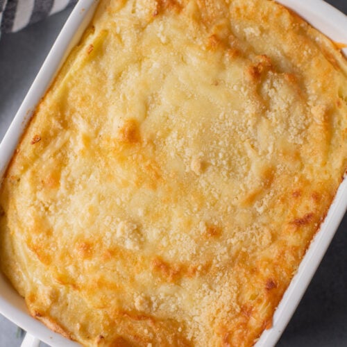 An overhead shot of a white casserole dish with healthy mashed potatoes on a grey background