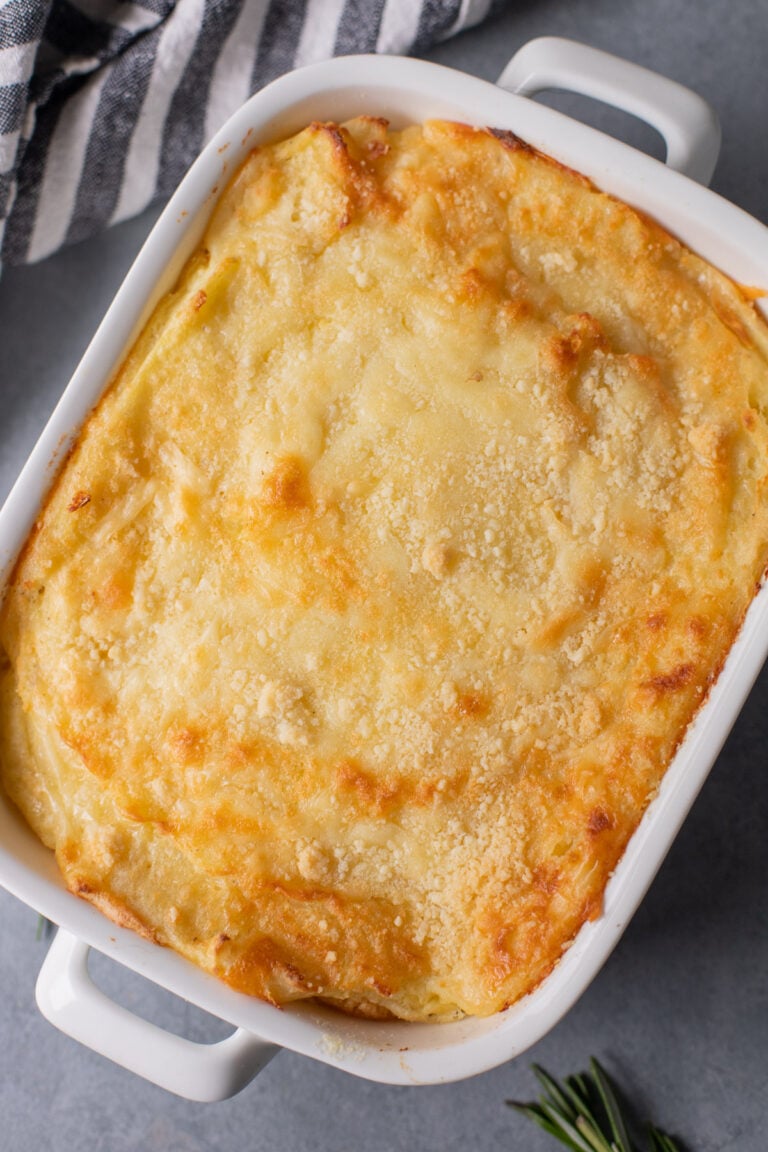 An overhead shot of a white casserole dish with healthy mashed potatoes on a grey background