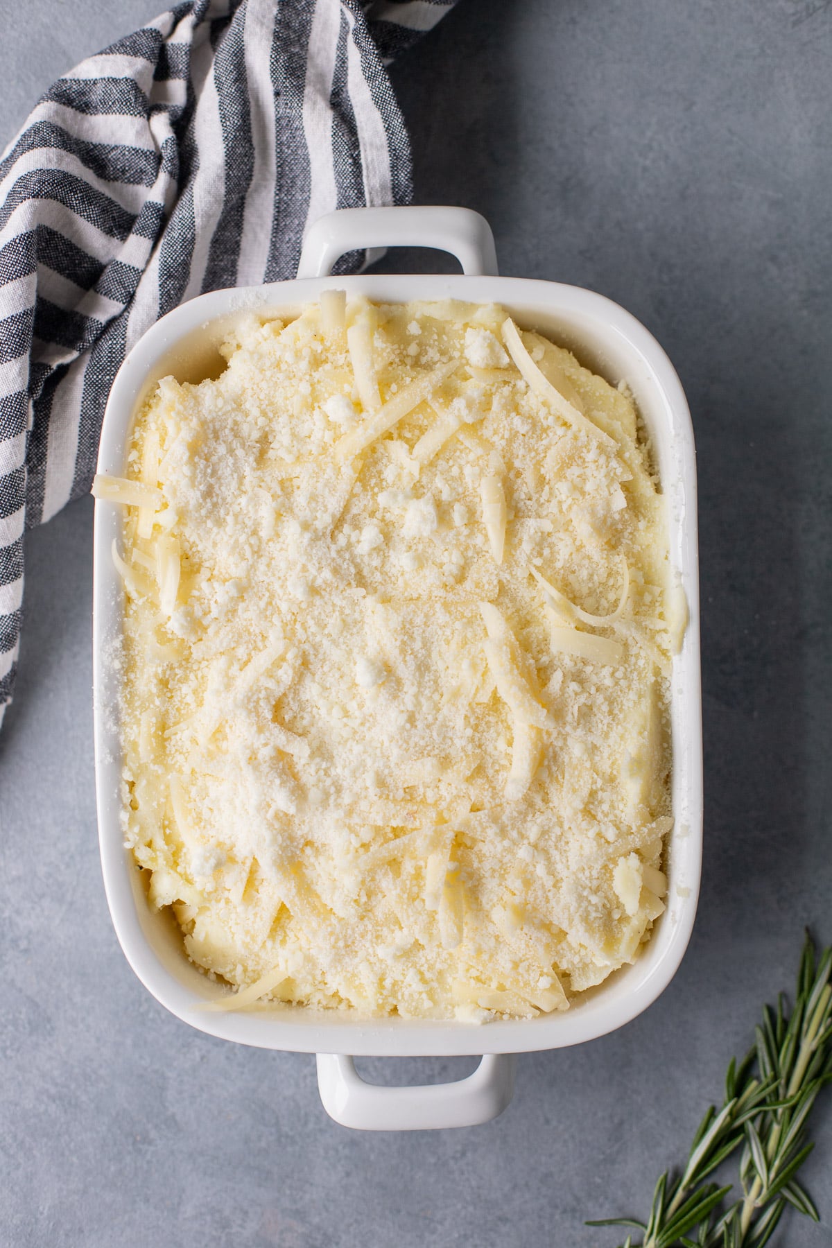 An overhead shot of a white casserole dish of healthy mashed potatoes before being baked