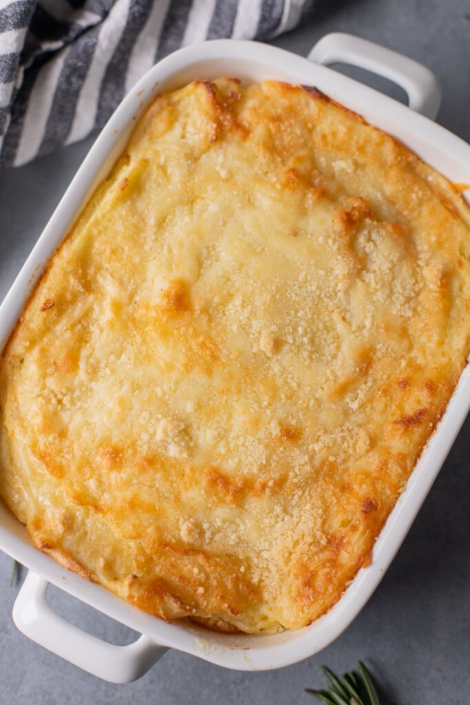 An overhead shot of a white casserole dish with healthy mashed potatoes on a grey background