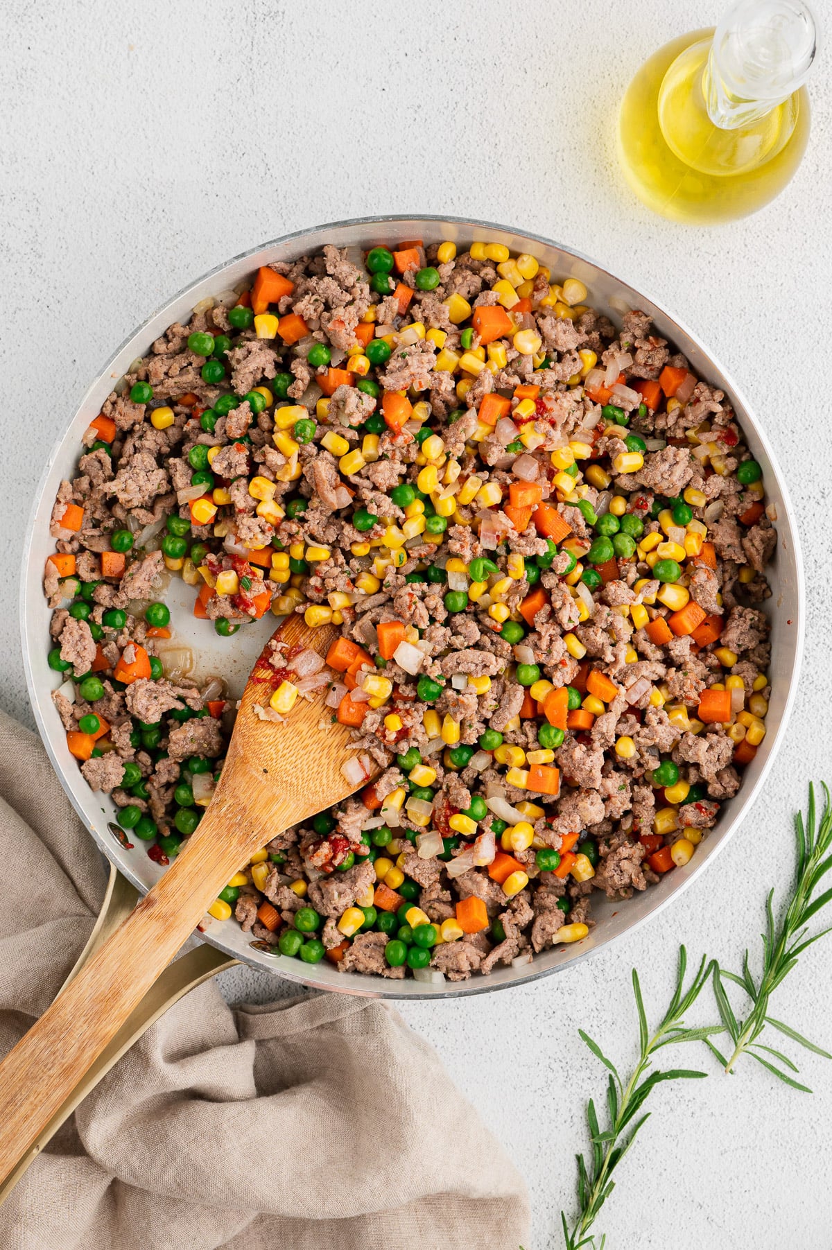 Ground turkey/veggie filling cooking in a pan for shepherd's pie being stirred with a wooden spoon on a white backgrouns
