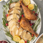 A close up of herb butter turkey on a plate with thanksgiving sides off to the side
