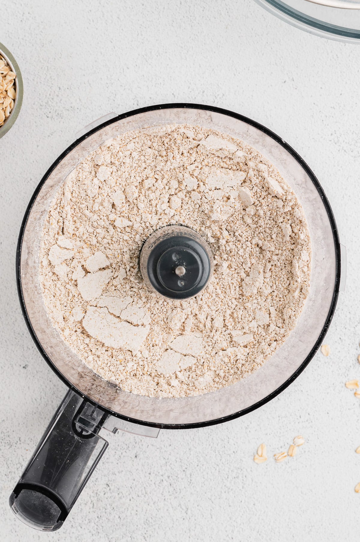 An overhead shot of a food processor with a powdery substance in it.