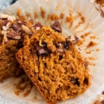 A halved sweet potato muffin with chocolate chips on a muffin paper on a white background