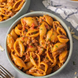 A close up of taco pasta in a green bowl on a grey background