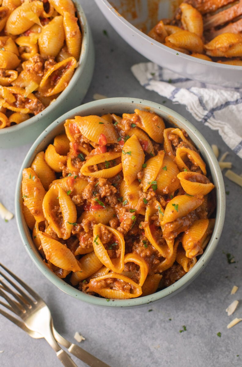 A close up of taco pasta in a green bowl on a grey background