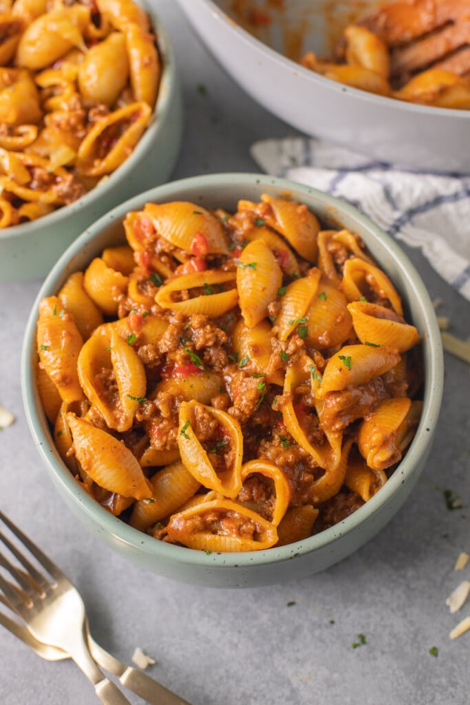 cheesy taco pasta in a green bowl on a grey background