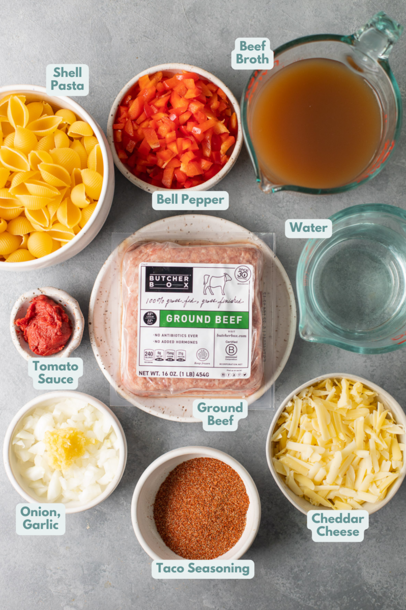 Ingredients for Cheesy Taco Pasta in small white bowls on a grey background