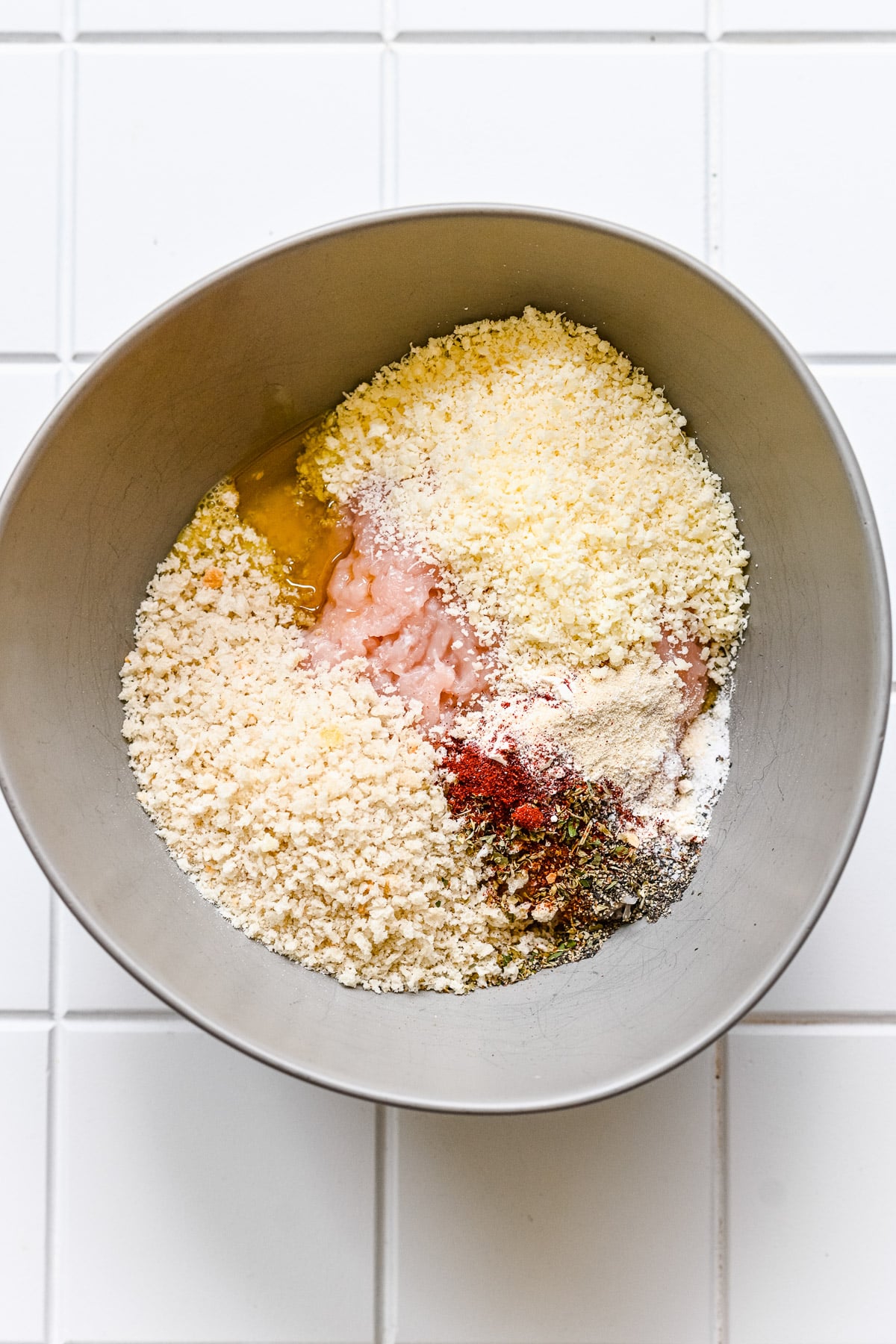 Ingredients for chicken meatballs in a grey bowl before being mixed