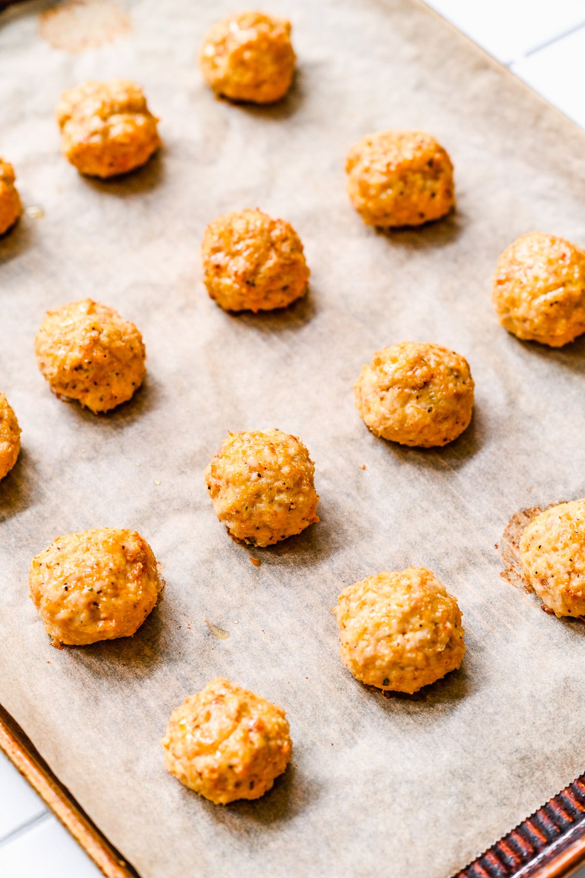 Chicken meatballs on a parchment lined baking sheet after being baked