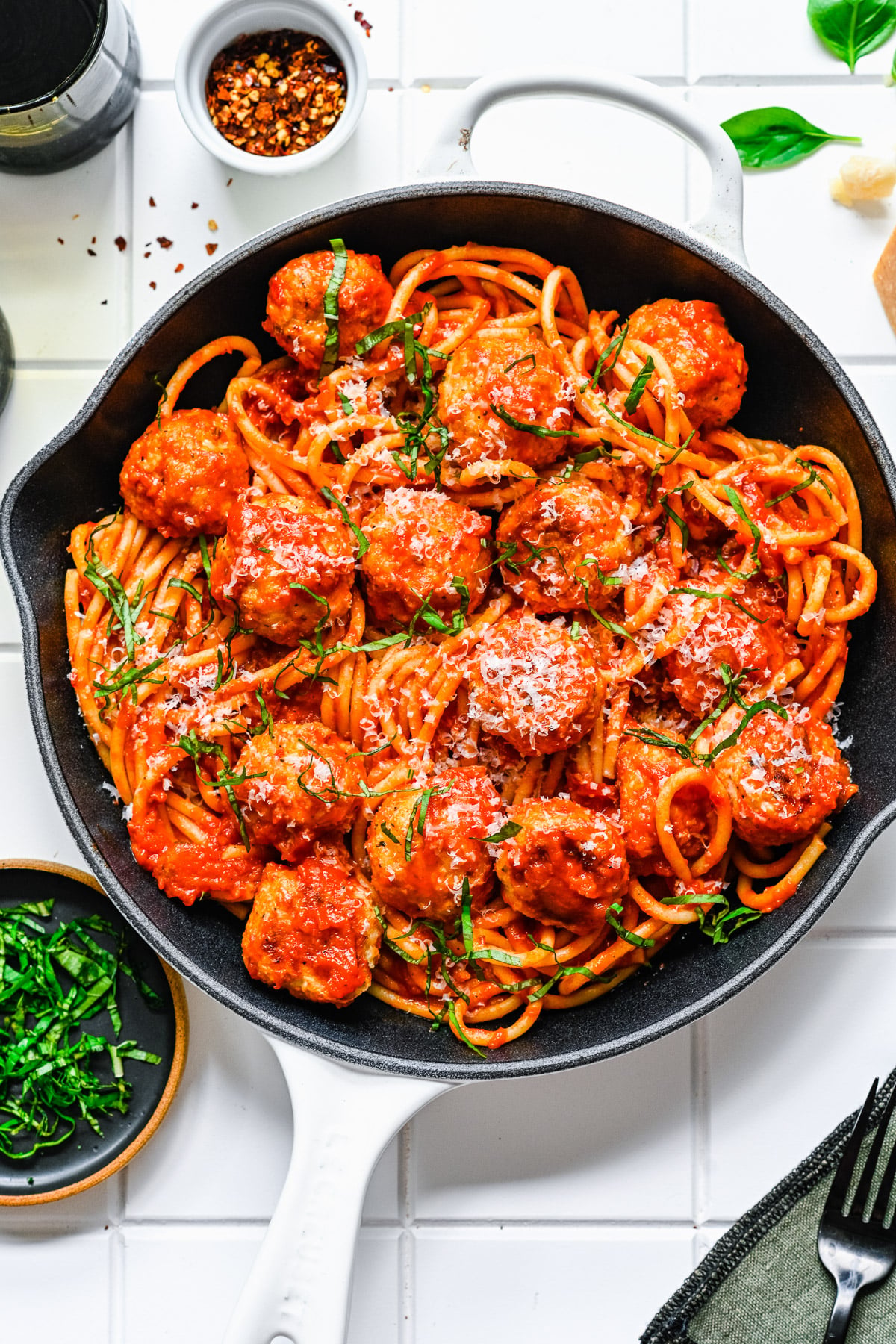 A large pan of chicken meatballs, spaghetti, and spaghetti sauce on a white background
