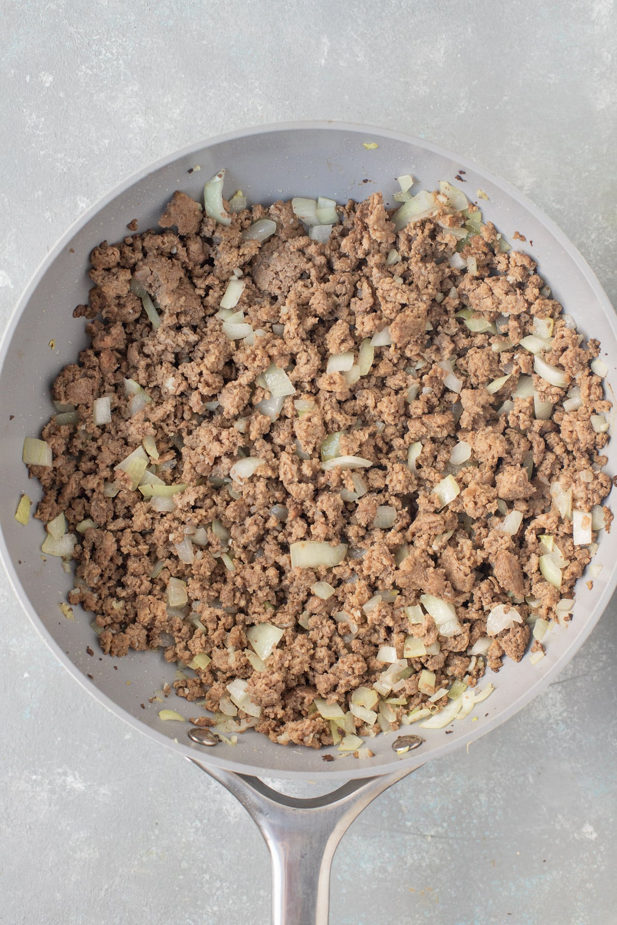 Ground beef, onions, and garlic in a pan after being browned for hamburger casserole