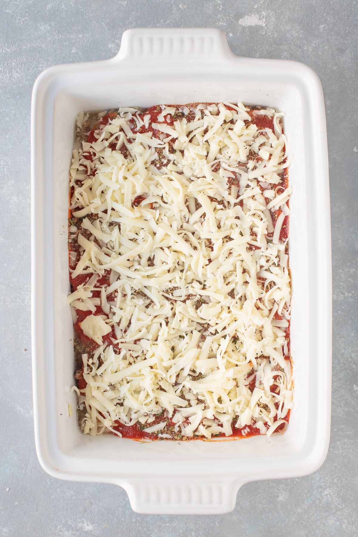 An overhead shot of a white baking dish of hamburger casserole before being baked