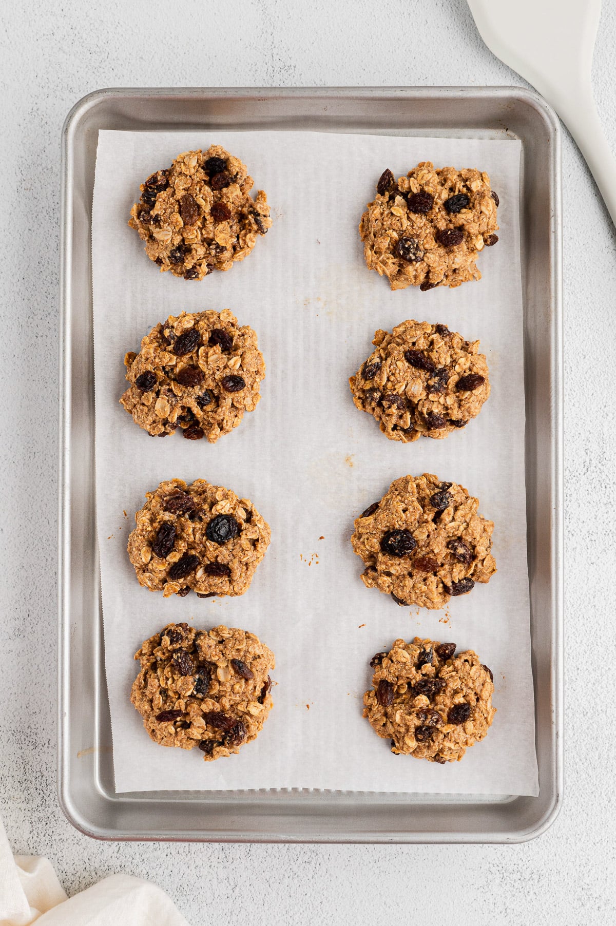 Baked Healthy Oatmeal Raisin Cookies on a lined baking sheet