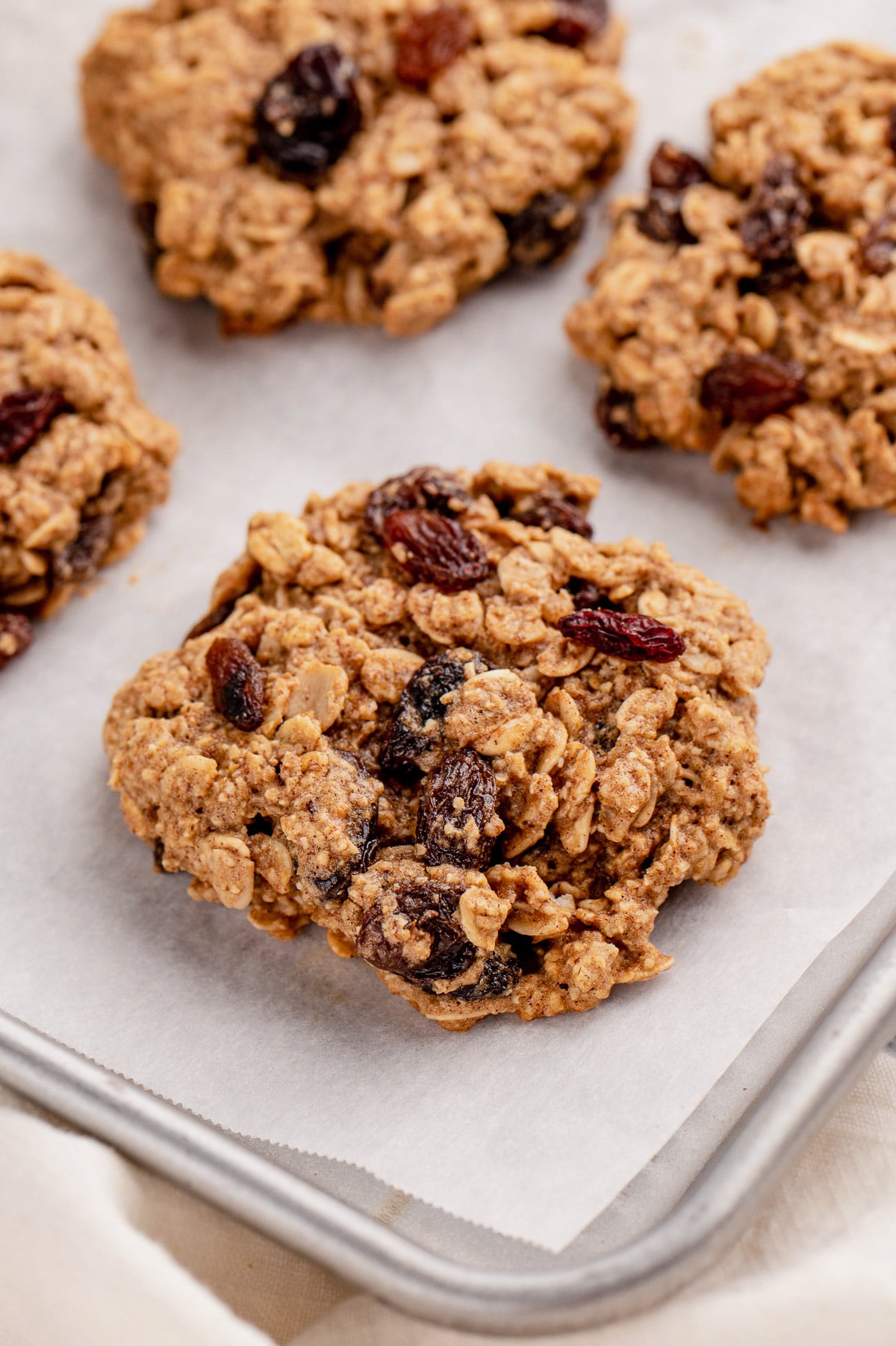 A close up of an oatmeal raisin cookie on a lined baking sheet