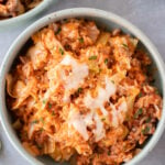 An overhead shot of an unstuffed cabbage rolls recipe in a bowl with another bowl on the side on a grey background