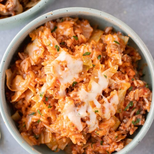 An overhead shot of an unstuffed cabbage rolls recipe in a bowl with another bowl on the side on a grey background