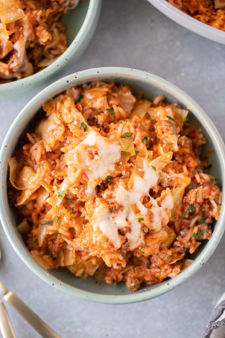 An overhead shot of an unstuffed cabbage rolls recipe in a bowl with another bowl on the side on a grey background