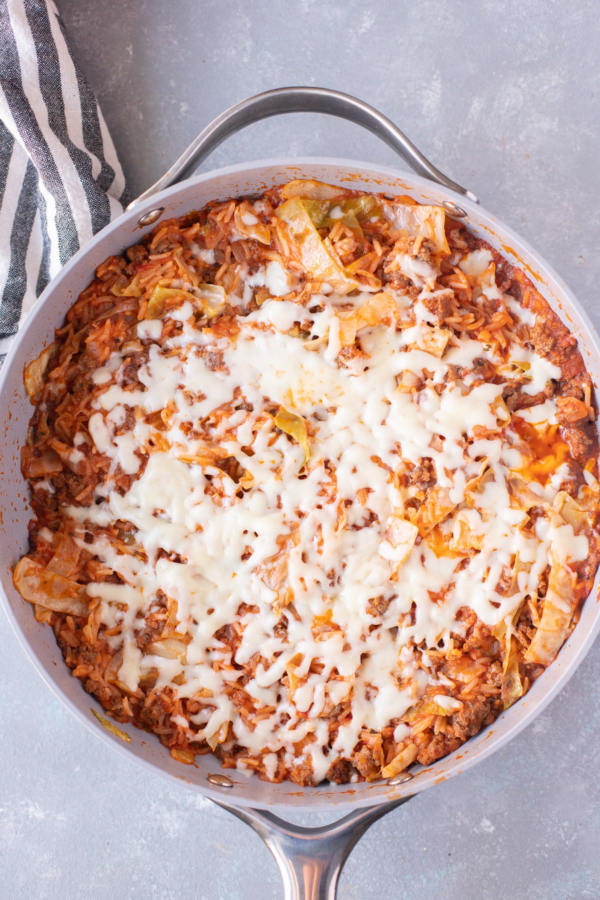 An overhead shot of a pan of unstuffed cabbage rolls with melted cheese on top